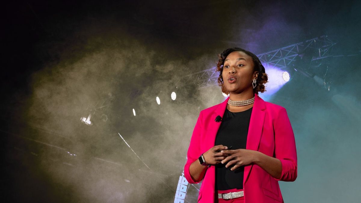 Jasmine Kelly speaking on stage under stage lights